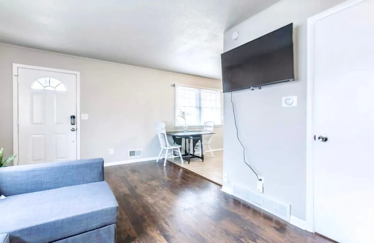 A cozy, multifunctional living space featuring a comfortable sofa, a dining table, and a television. The decor is warm and inviting, suggesting a perfect spot for family relaxation, movie nights, or shared meals after a day exploring the city.