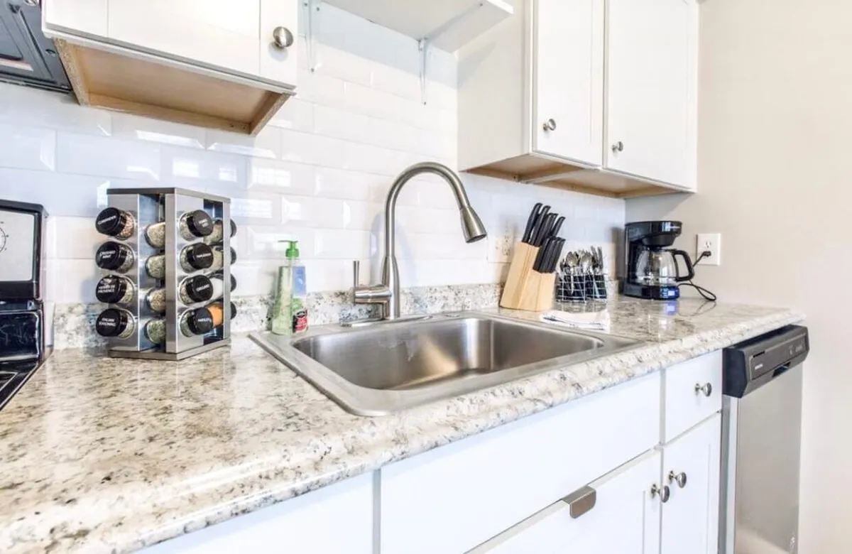 A kitchen scene with a focus on the sink, spacious countertop, spice rack, and coffee maker, presenting a functional and welcoming workspace ideal for both quick routines and more elaborate meal preparations.